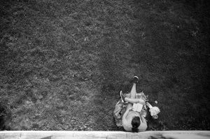 A person leaning against a wall with a book.