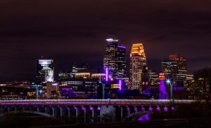 The skyline in Minneapolis, with buildings and bridges illuminated in purple.