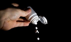 A person upending a bottle of pills.