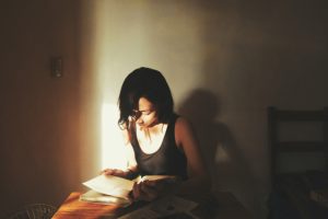 A person reading in a shaft of light.