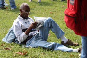 A person reading a newspaper on a lawn.