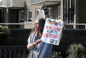 A person holding up a sign that says RACISM HURTS EVERYONE
