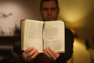 A person thrusting a Bible out at the camera.