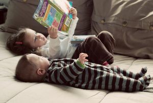 Two children lying on a couch, reading.