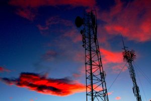 Radio tours silhouetted against the sky at sunset.
