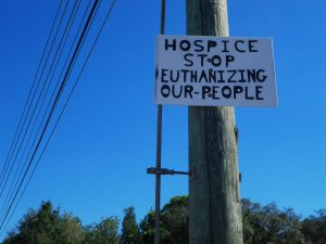 A sign: HOSPICE STOP KILLING OUR PEOPLE