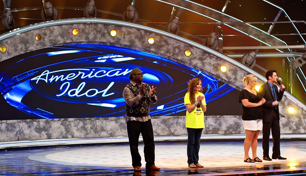 Performers singing on an American Idol stage.