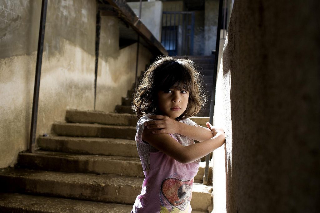 A girl in a pink shirt on a flight of stairs.