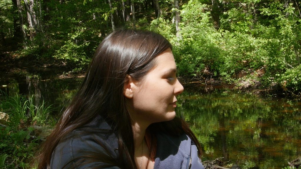 A woman sitting by a river in GONE.