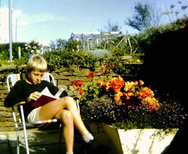 A person lounging in a chair reading outside.