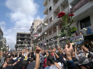 Protesters in Syria in 2011 holding roses as they march down the street.