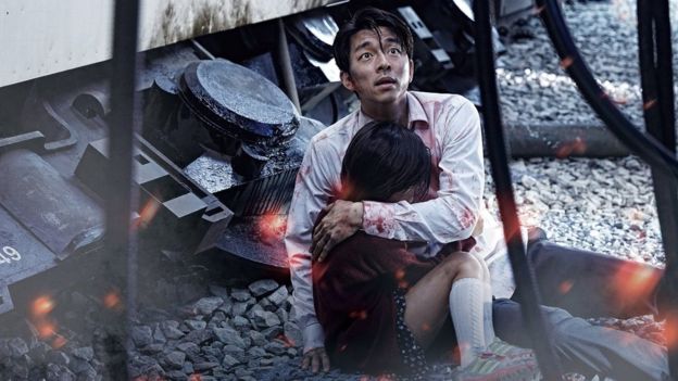 A still from Train to Busan with two characters cowering in fear next to a train.