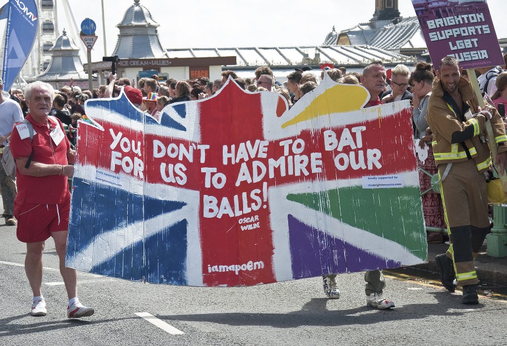 Marchers at a gay pride parade carrying a sign reading YOU DON'T HAVE TO BAT FOR US TO ADMIRE OUR BALLS