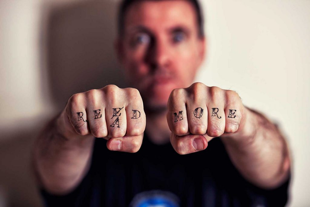A man with lettering that says READ MORE on his knuckles.