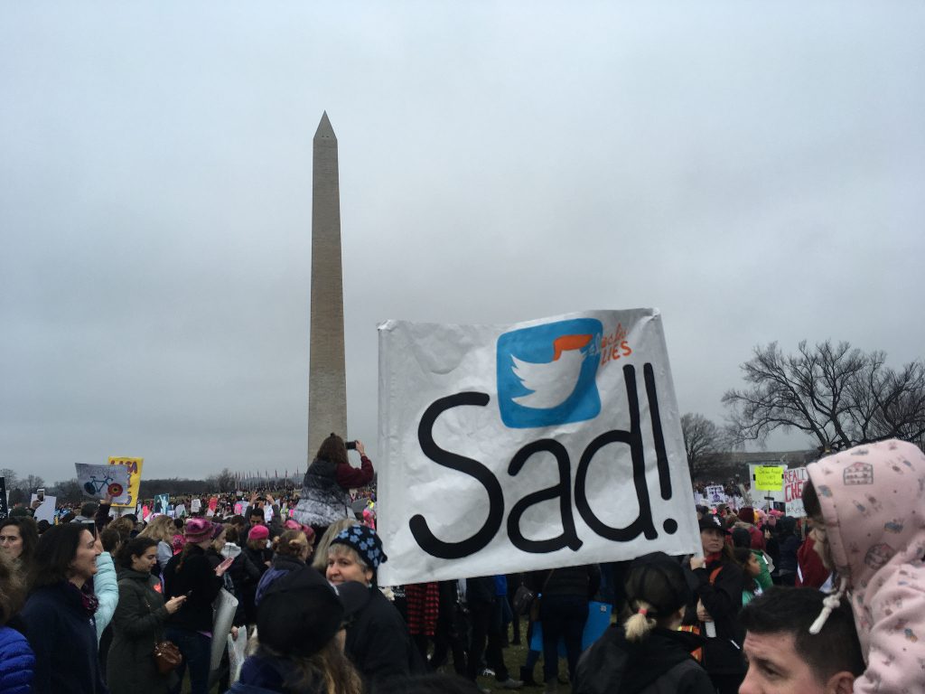 A protester holding up a sign with the Twitter logo and the word SAD!