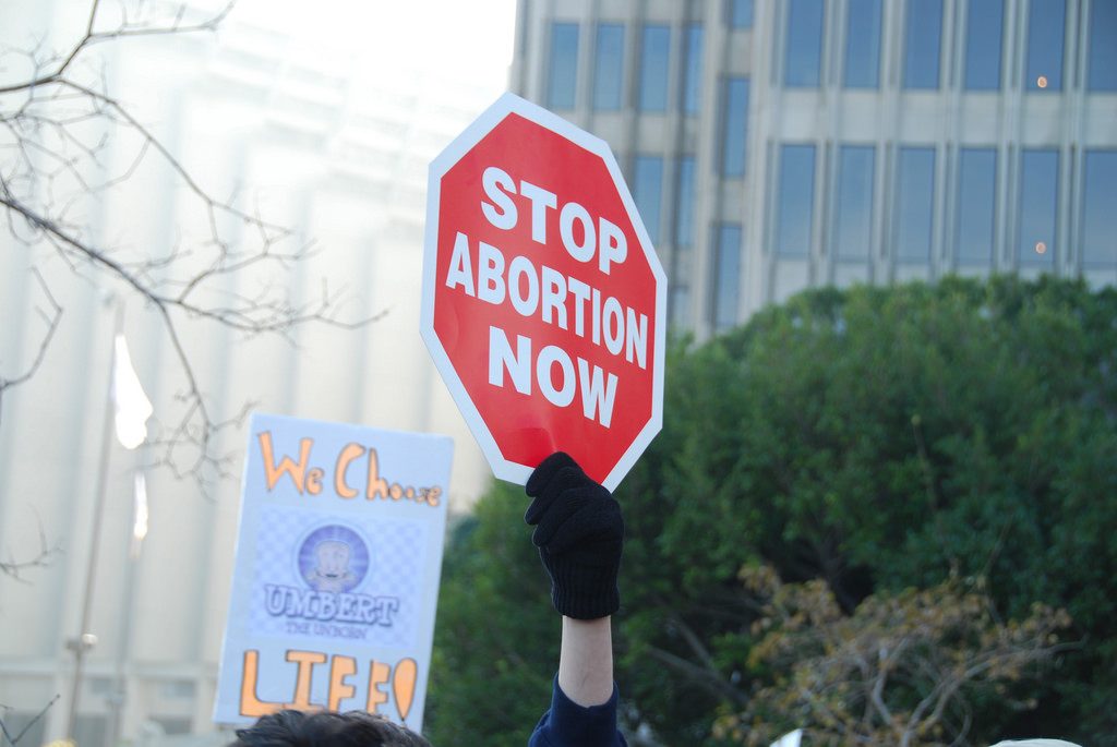 A protester holds up a sign: STOP ABORTION NOW.