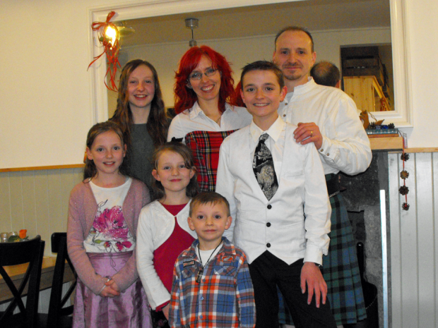 A smiling white family wearing tartans.