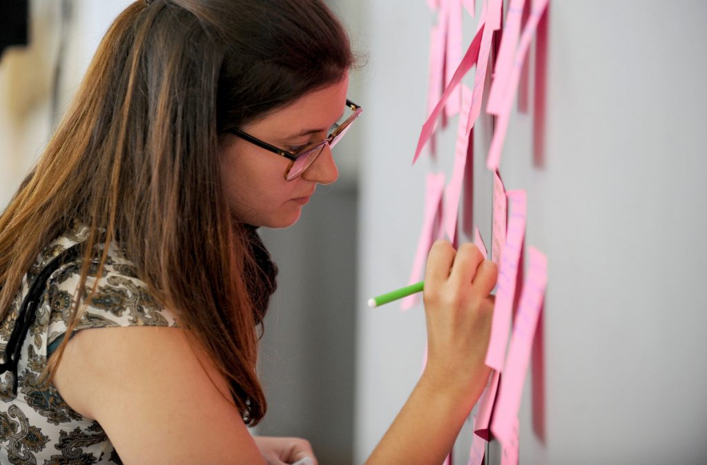 A young person writing on a postit.