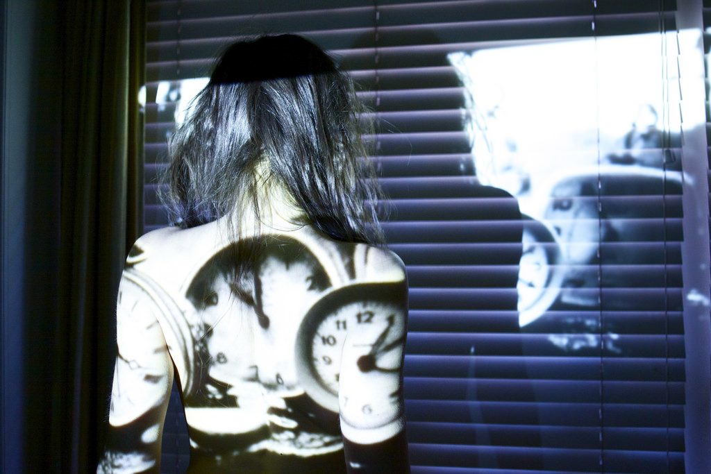 A photocomposite of a woman with clocks on her back.