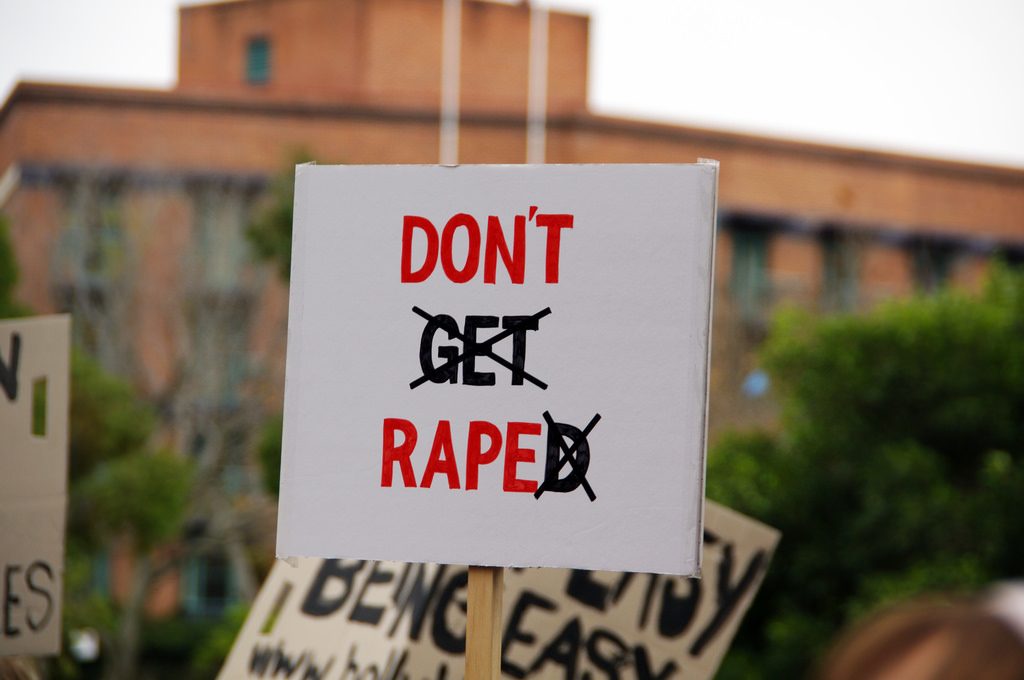 A protester holding a DON'T RAPE sign