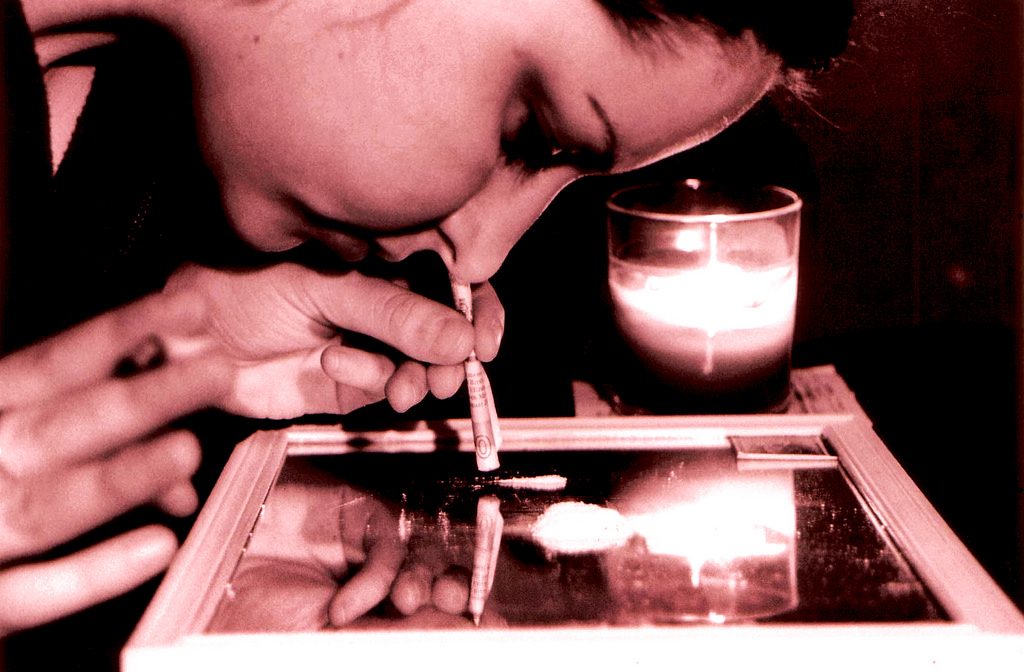 A person snorting a powdery substance off a mirror